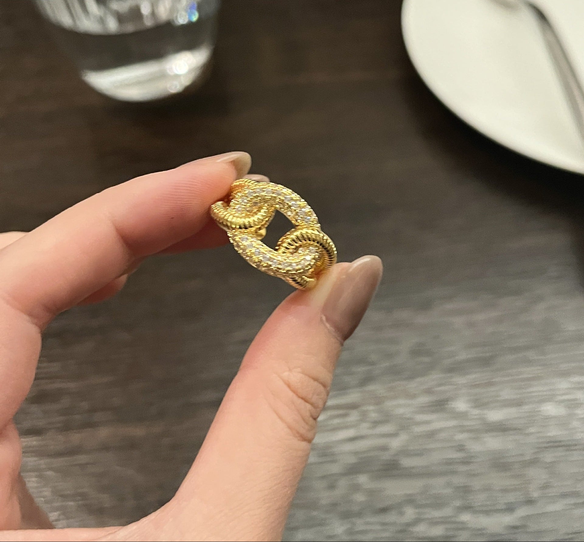 Gold ring held by a hand on a blurred background