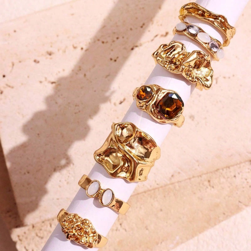 Gold rings with gemstones on a beige surface