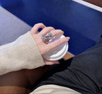 Hand holding a coffee cup with two rings on a blurred background