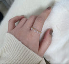 Hand wearing a delicate gold ring with small stones on a white background