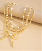 Gold beaded necklace with a bow detail on a beige background