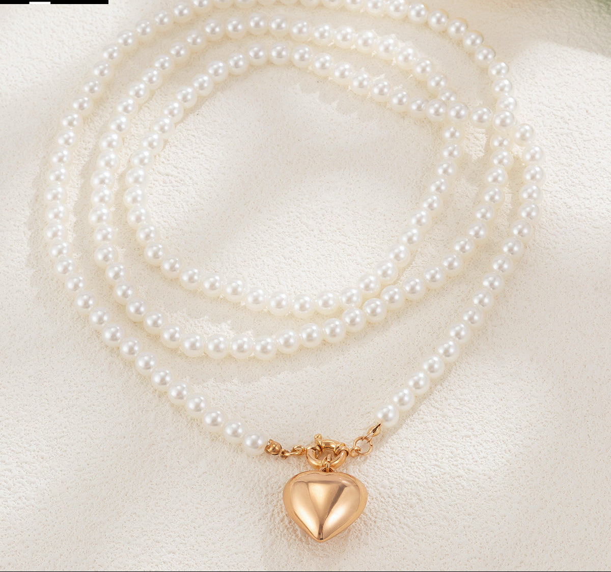 Pearl necklace with a gold heart pendant on a light background