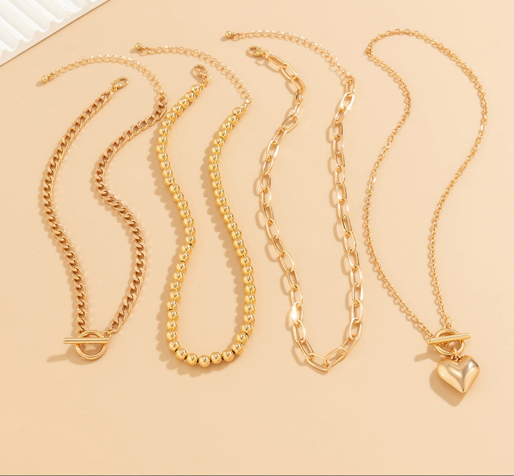 Four gold necklaces on a beige background