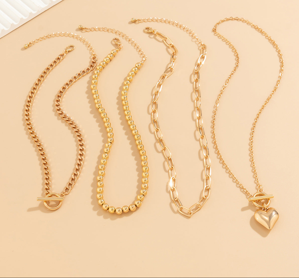 Four gold necklaces on a beige background