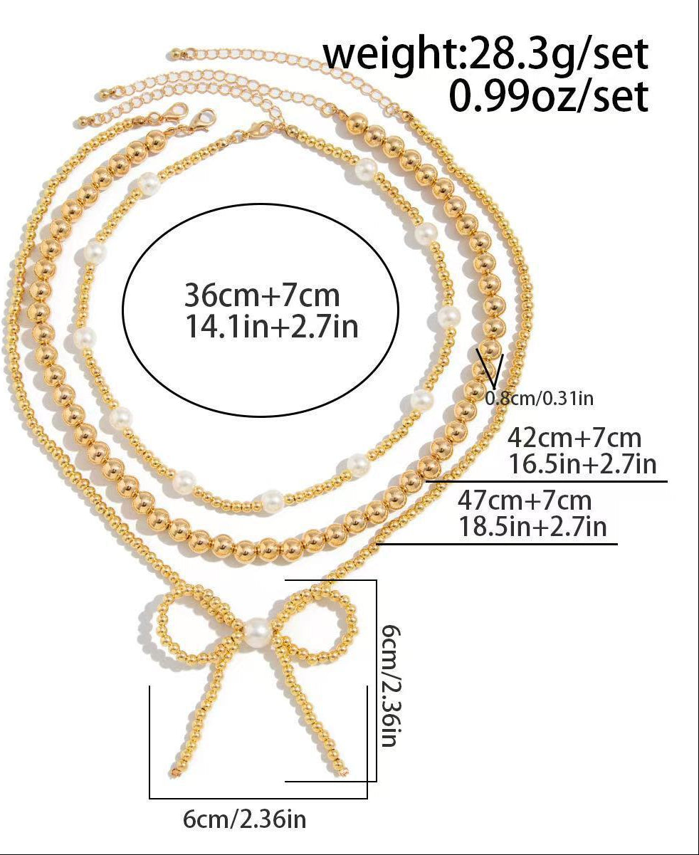 Gold necklace with bow pendant and measurements on a white background