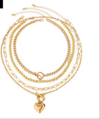 Gold chain necklace with a heart pendant on a white background