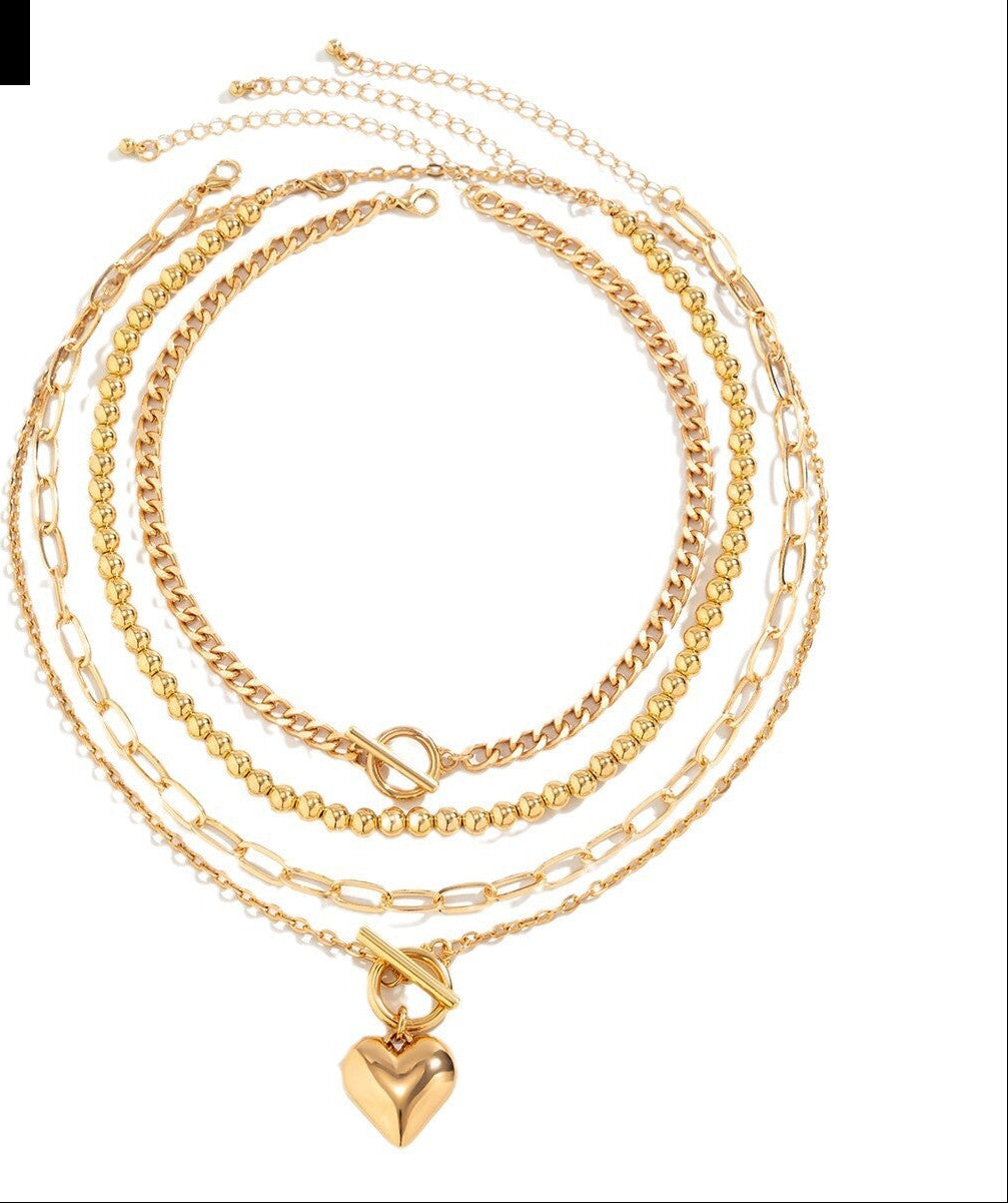 Gold chain necklace with a heart pendant on a white background