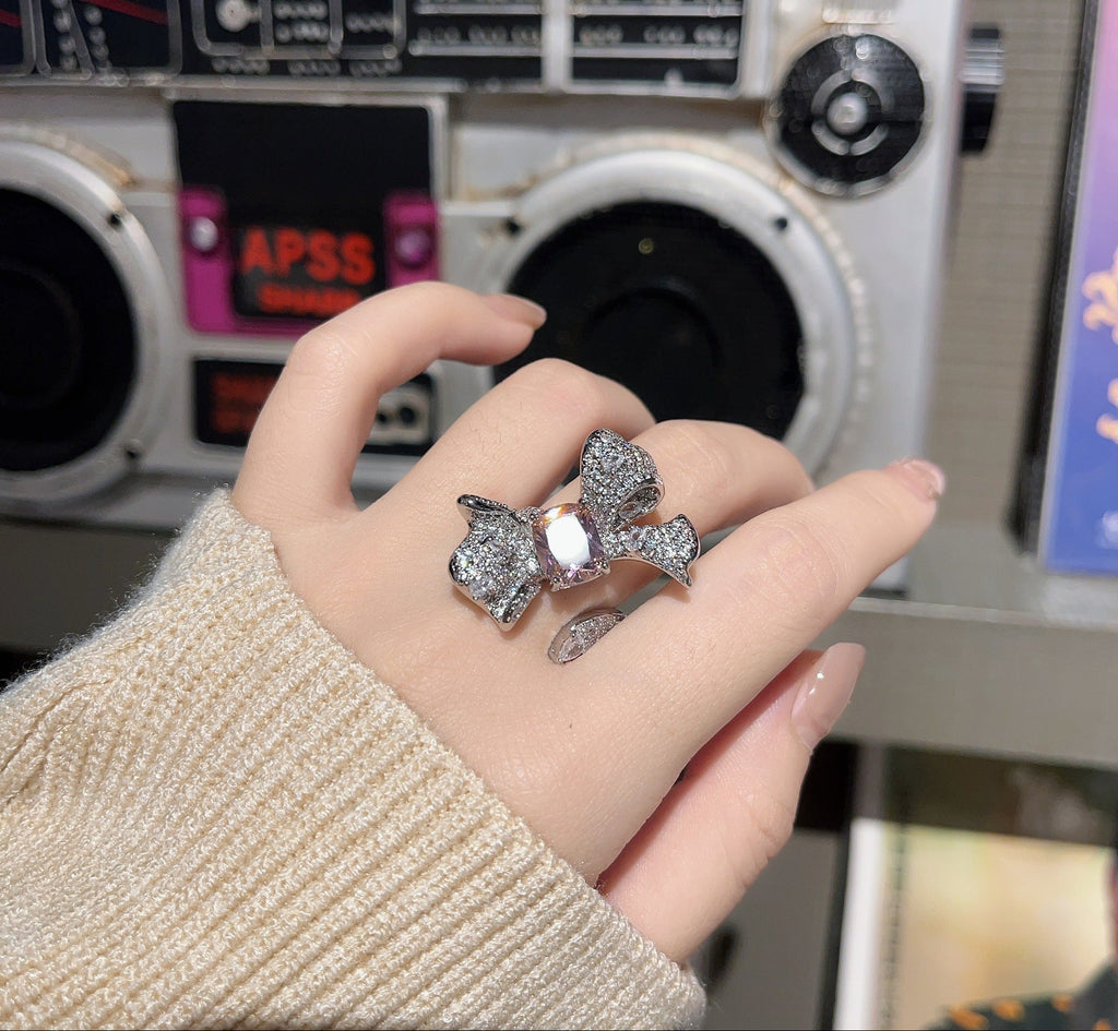 Hand wearing a silver ring with a clear gemstone in front of a vintage radio.