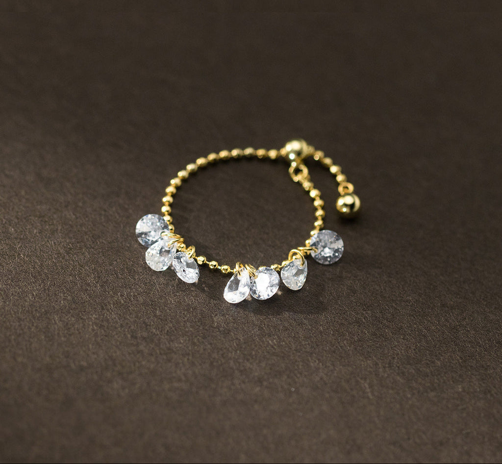 Gold ring with clear gemstones on a dark brown background