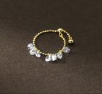 Gold ring with clear gemstones on a dark brown background