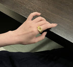 Hand wearing a gold ring on a wooden surface
