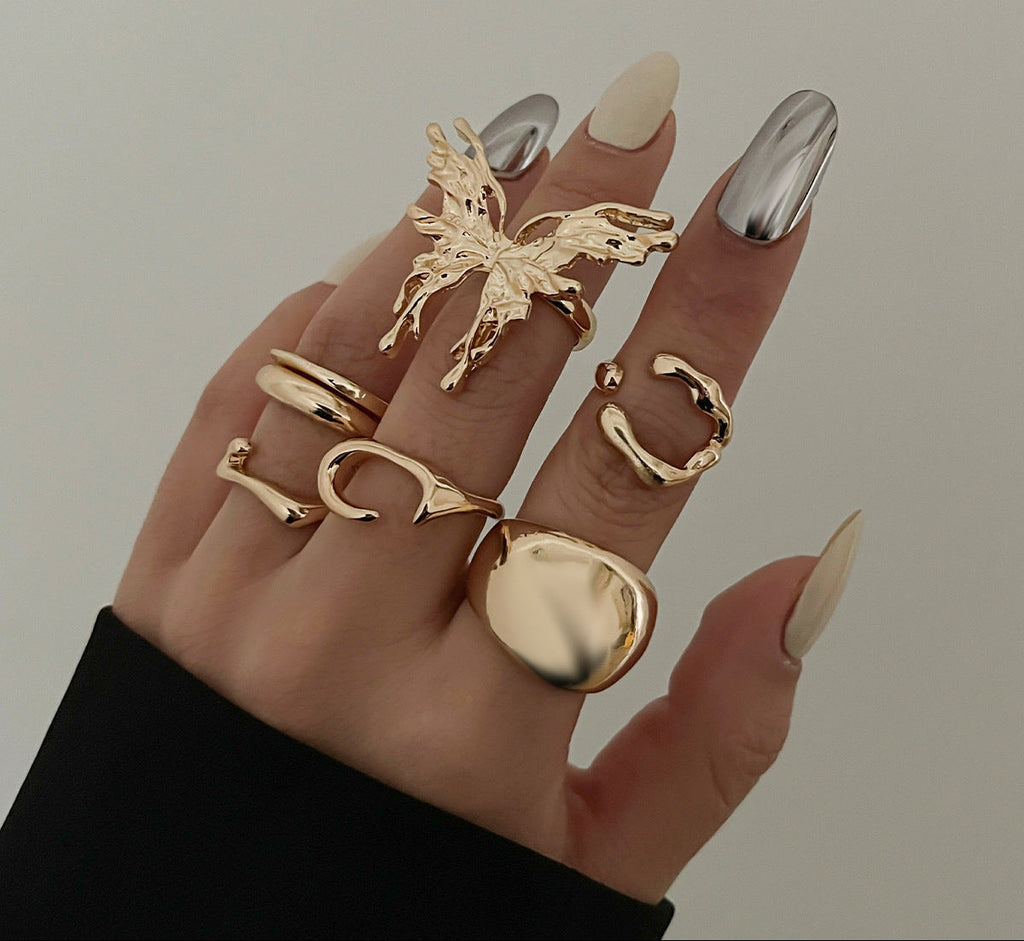 Hand wearing multiple gold rings with a plain background