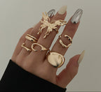 Hand wearing multiple gold rings with a plain background
