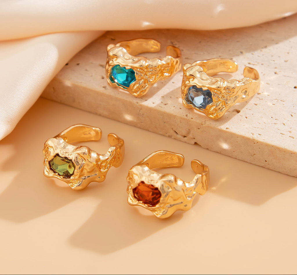 Gold rings with colored gemstones on a beige surface