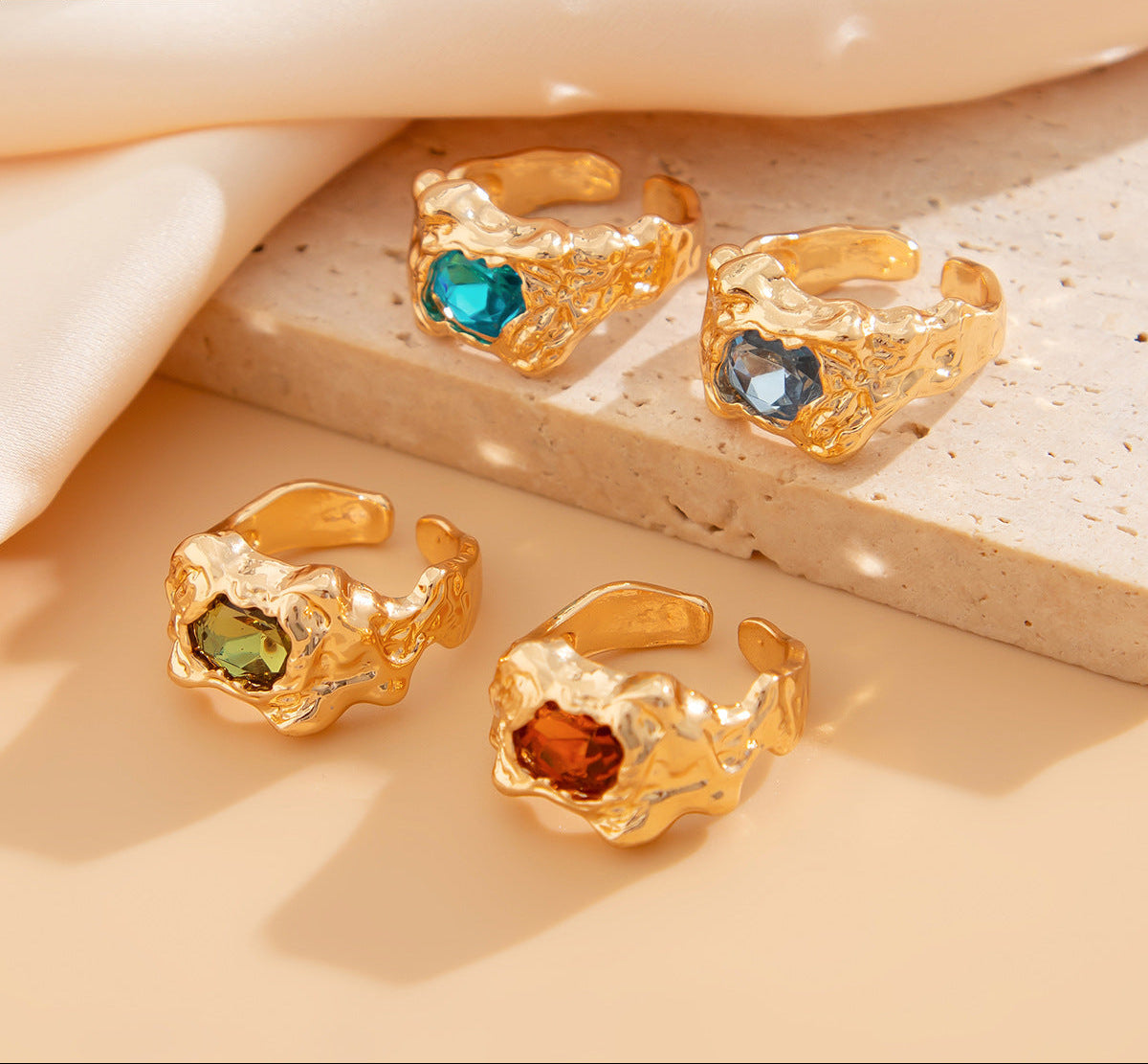 Gold rings with colored gemstones on a beige surface
