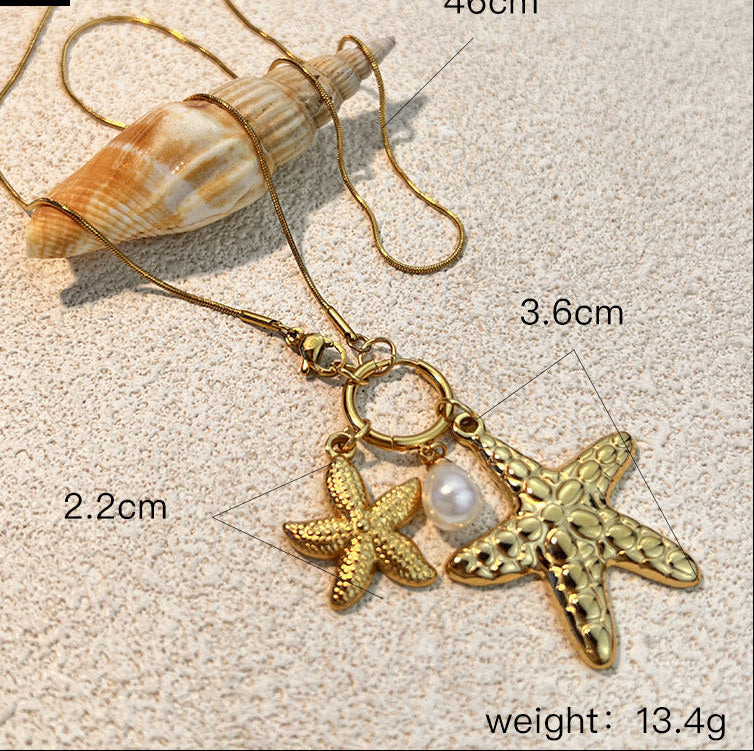 Gold necklace with starfish and pearl pendant on sand, showing measurements.