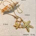 Gold necklace with starfish and pearl pendant on sand, showing measurements.