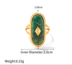 Gold ring with green stone and measurements on a white background
