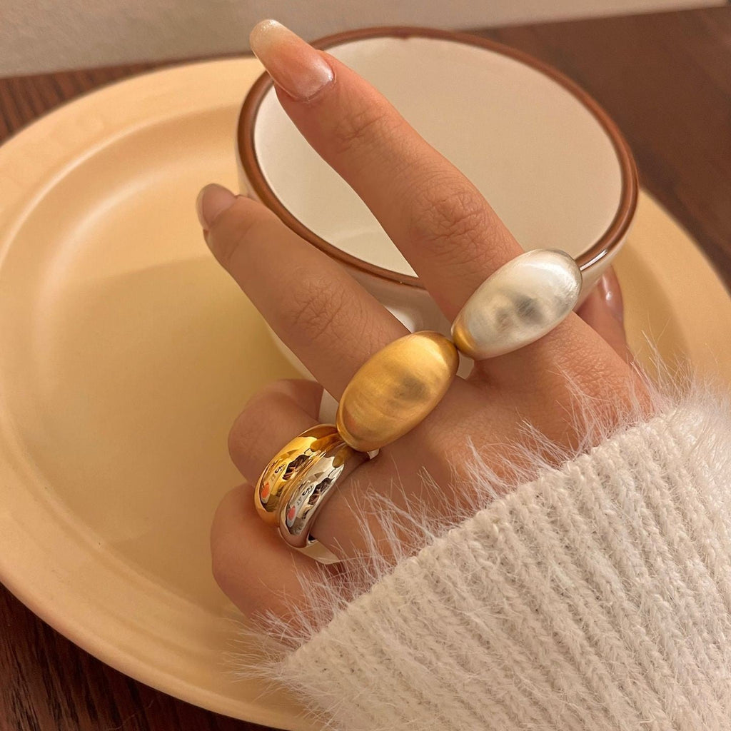 Hand wearing multiple rings with a neutral background