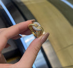 Gold ring with diamonds held between two fingers against a blurred background